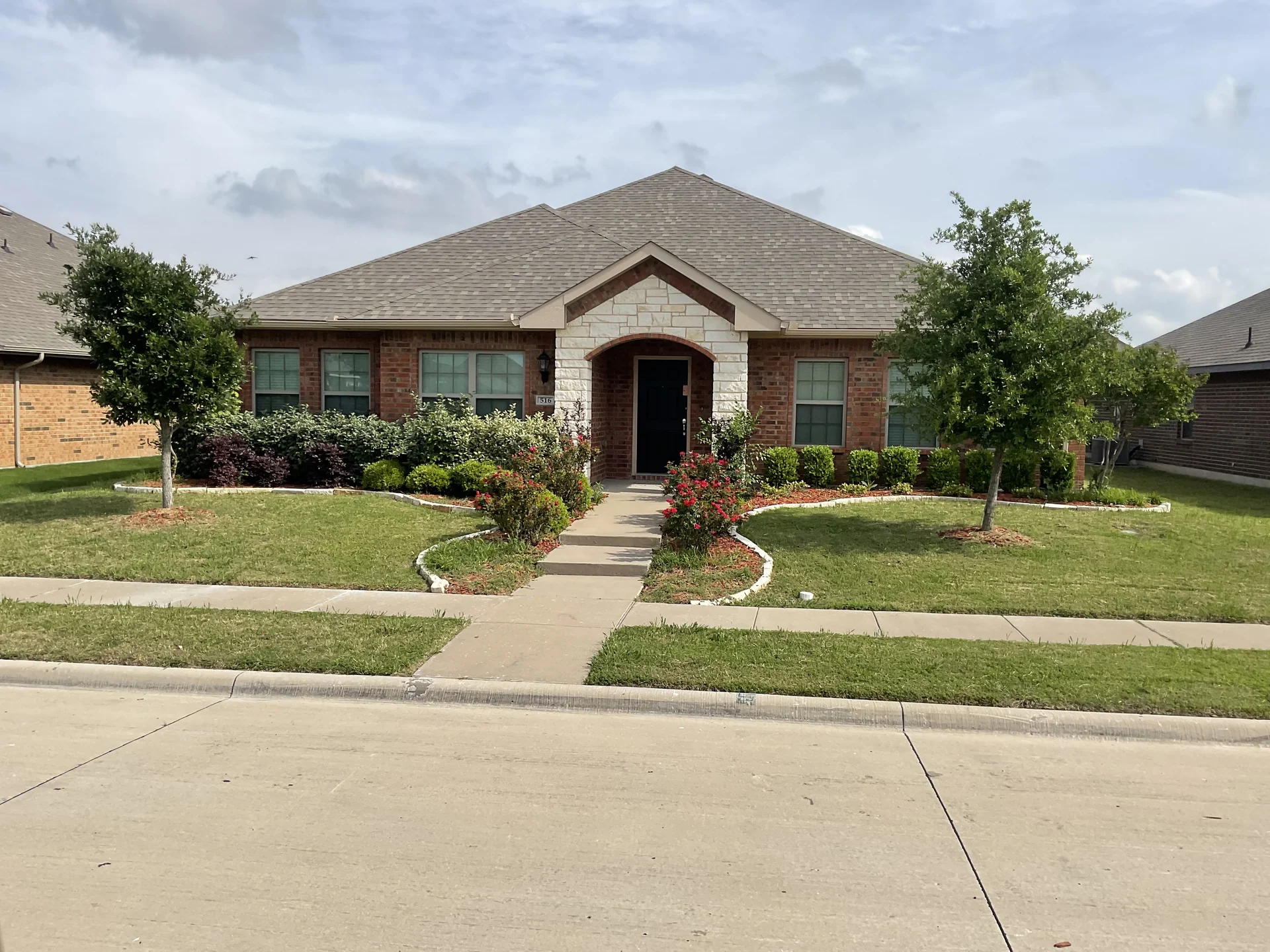 Clean low-water xeriscape garden beds and brick walkway in DFW master planned community