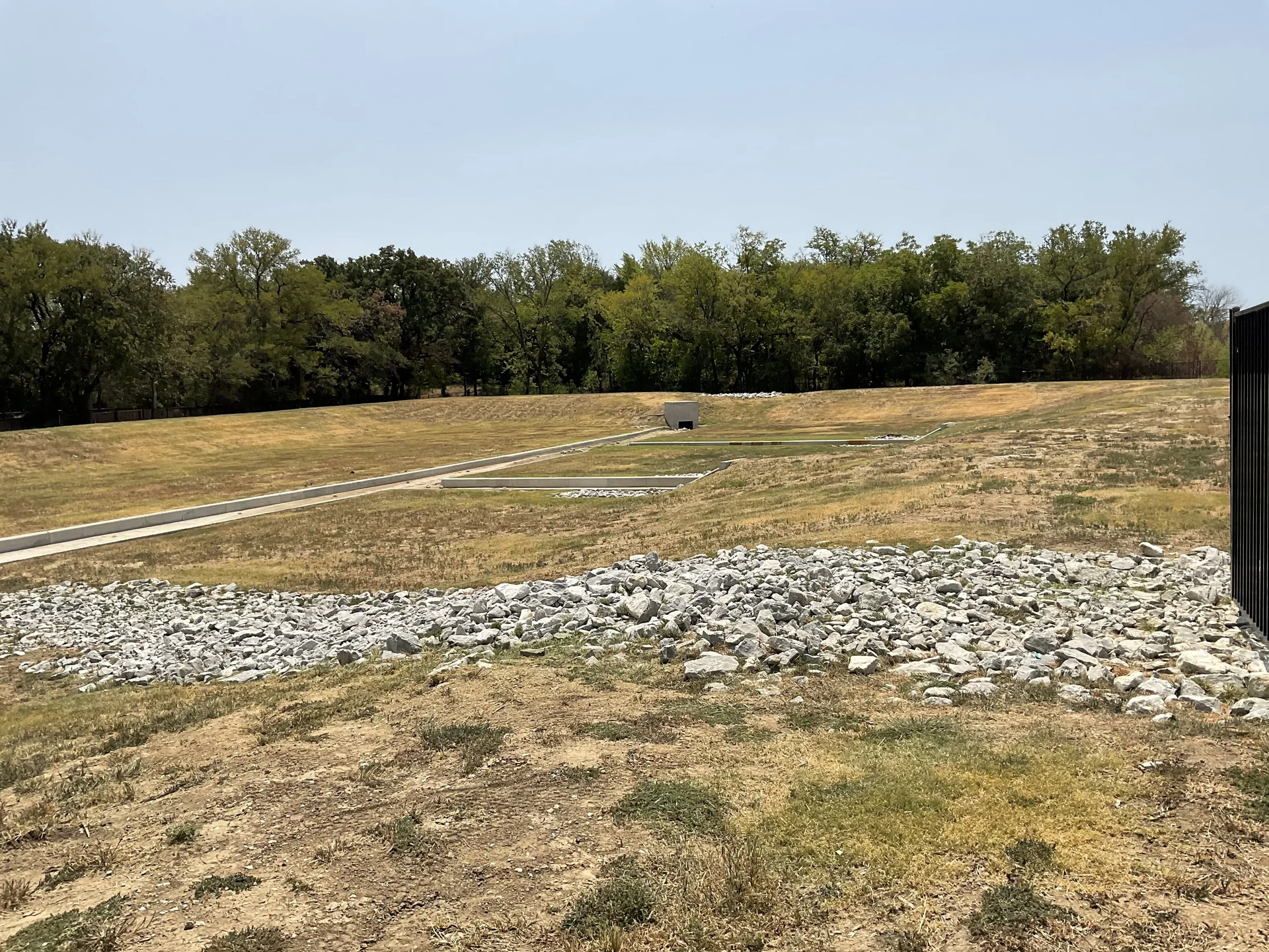 Excavated drainage trench with washed river stone and rigid perforated drainage pipe installation