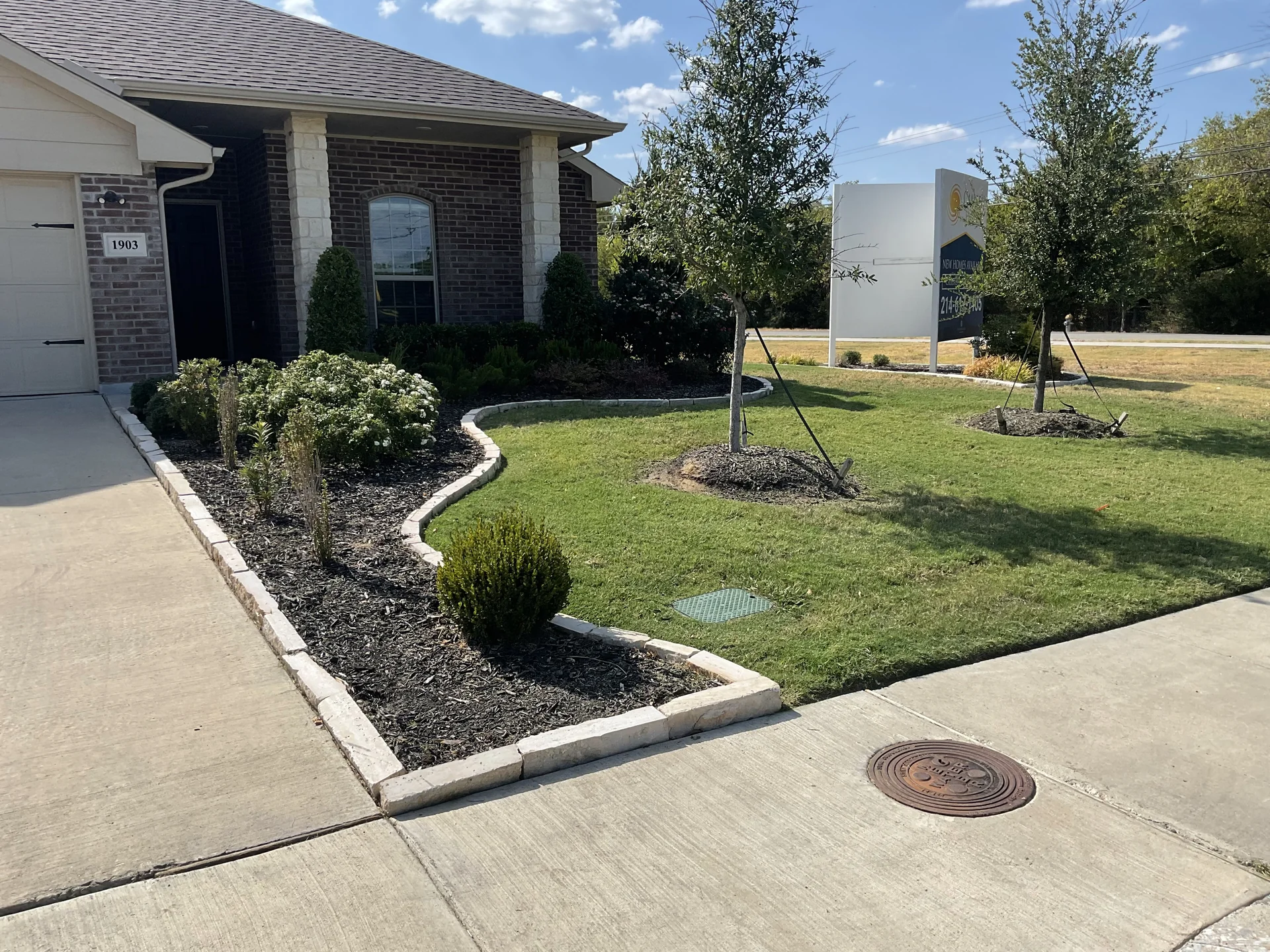 Fresh dark shredded hardwood mulch cleanly edged along curved concrete pathway
