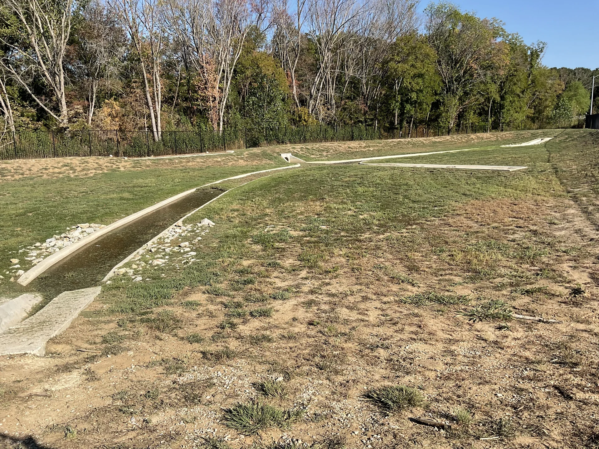 Natural stone dry creek bed surface swale integrated with subsurface french drain discharge