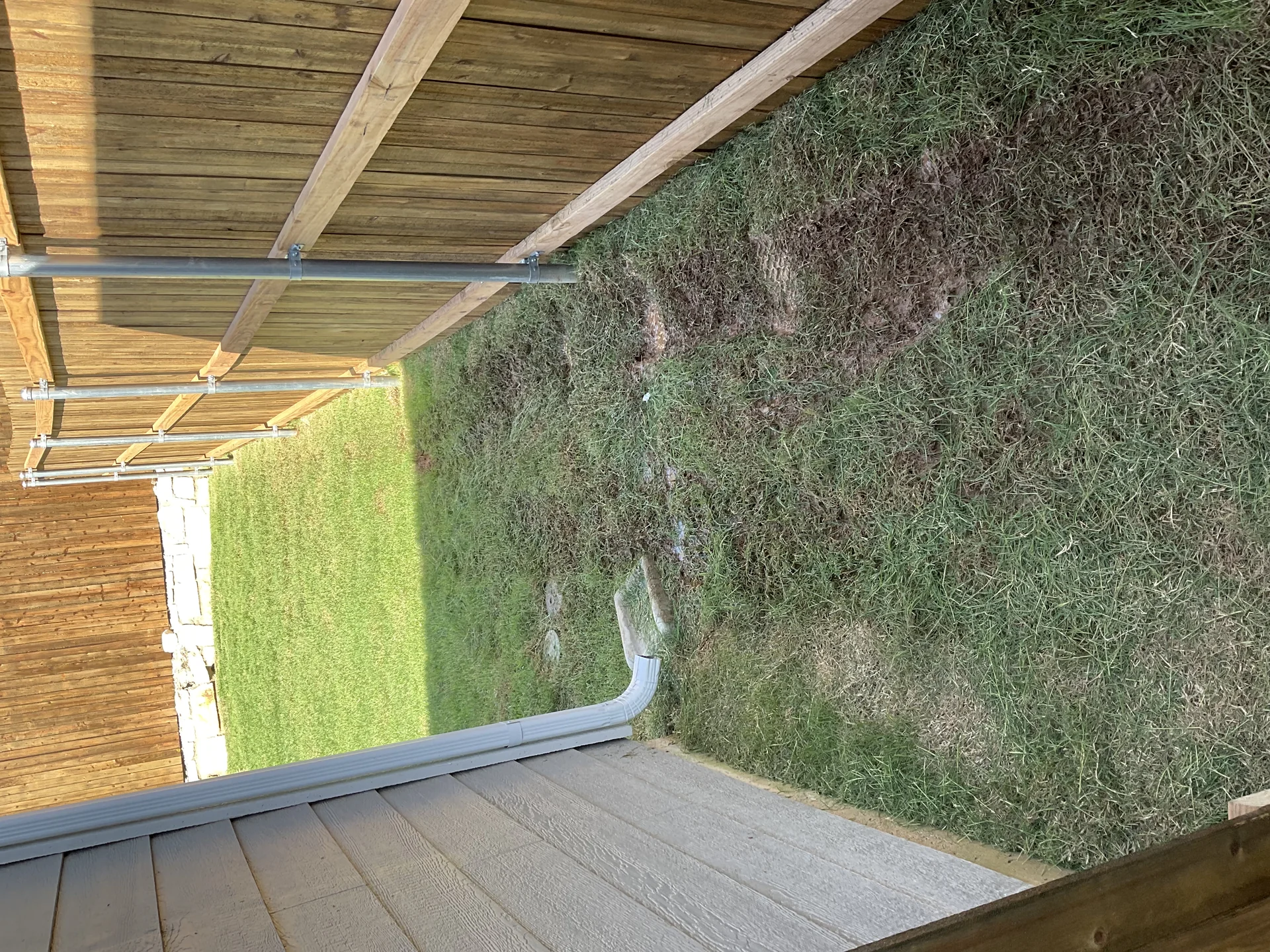 Downspout extension piping roof runoff away from foundation onto slope
